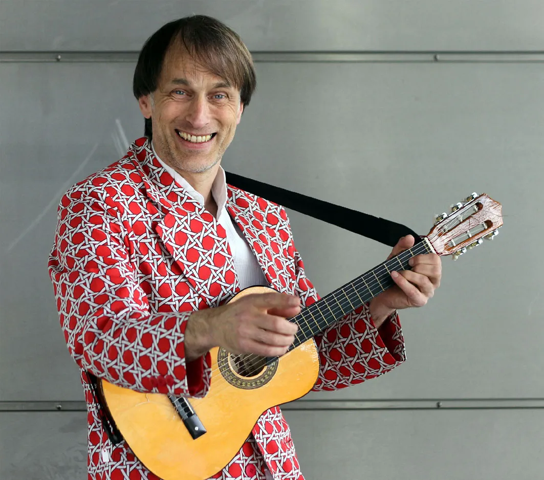 Thommi Baake lachend mit Gitarre
